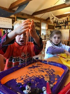 Child playing with orange slime at a table