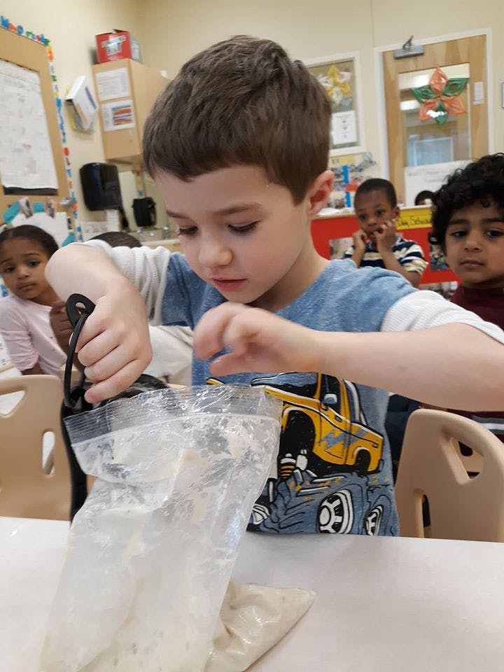 Child mixing contents in a plastic bag in a classroom