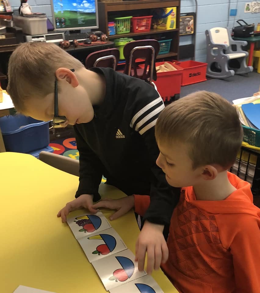 Two children looking at cards on a table in a classroom