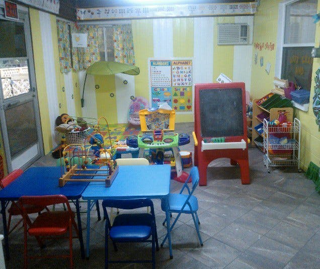 Classroom with small blue tables and chairs, toys, and a red easel