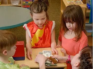 Children playing with toy money at a table