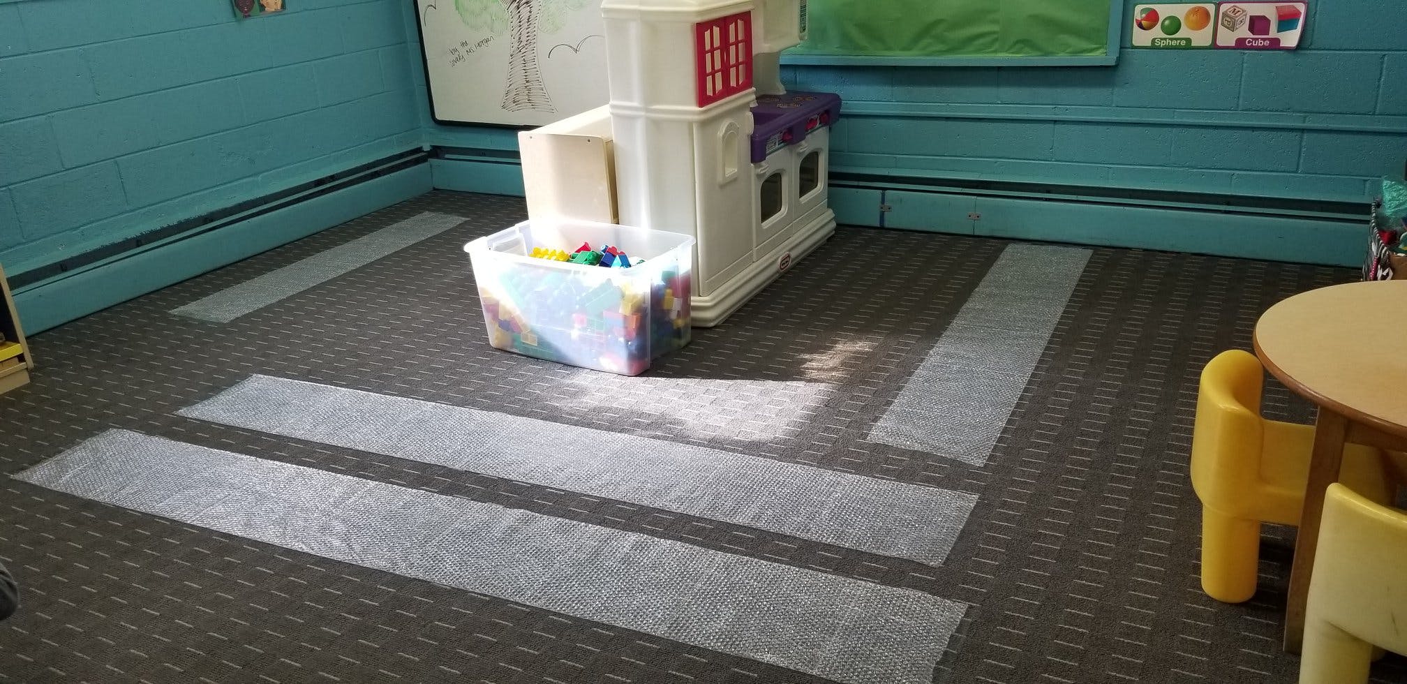 Classroom with play kitchen, toy bin, and child-sized table and chairs