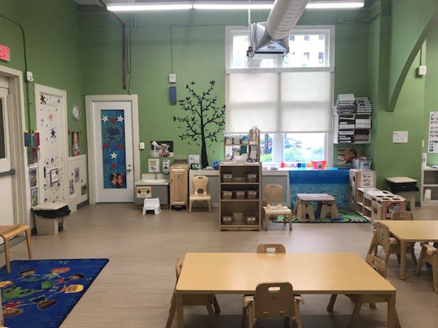 Classroom with small tables and chairs, green walls, and a large window