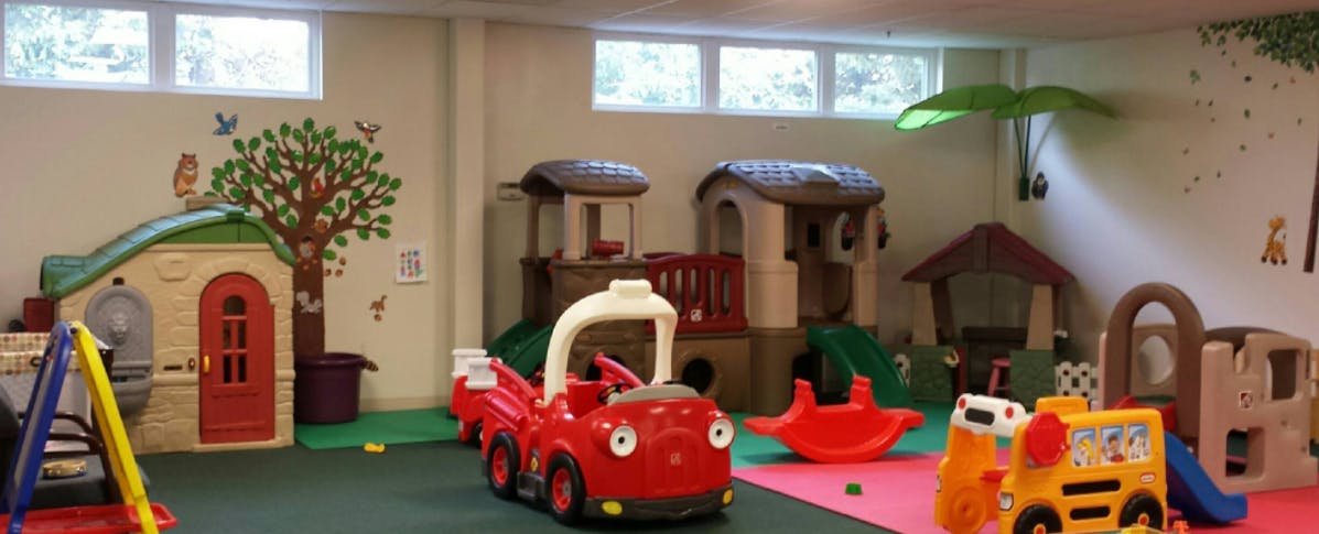 Indoor play area with various playhouses and ride-on toys