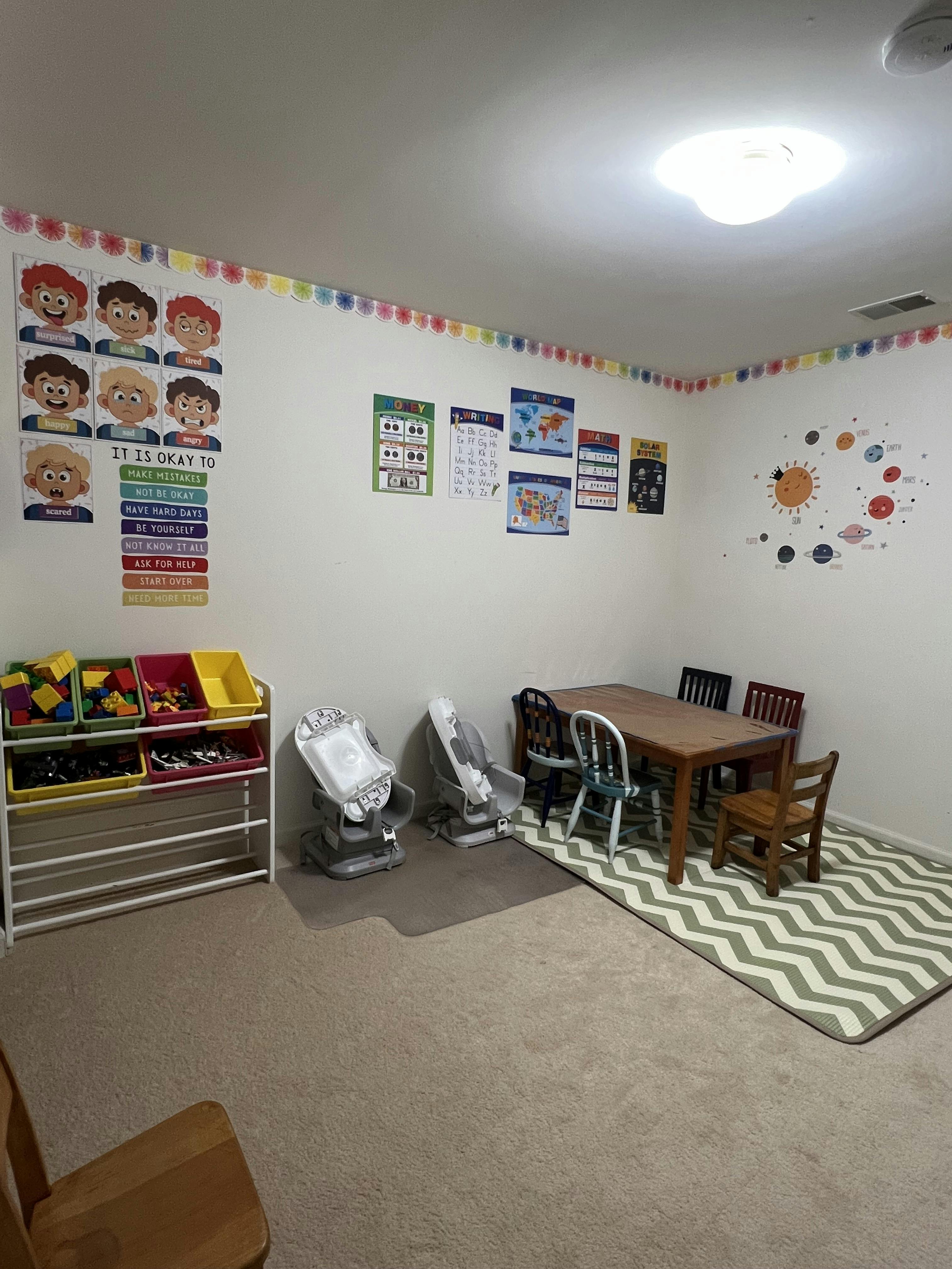 Children's play area with a table, chairs, toy storage, and wall decorations