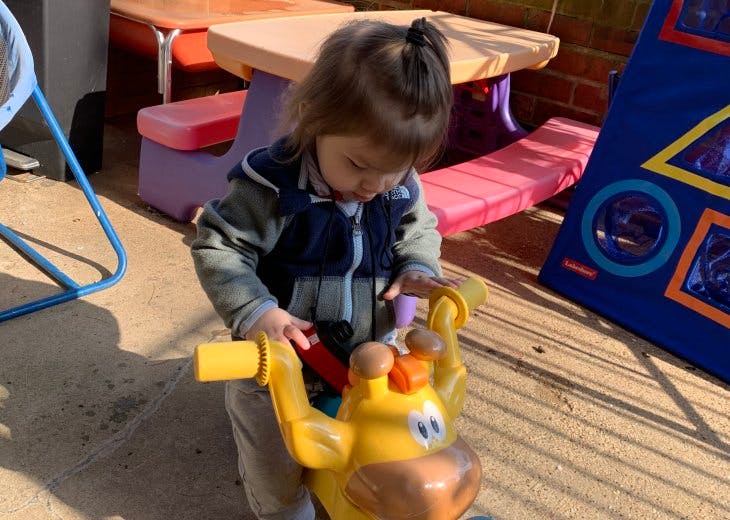 Child playing with a yellow ride-on toy