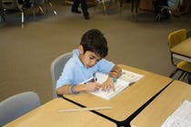 Child writing at a desk in a classroom
