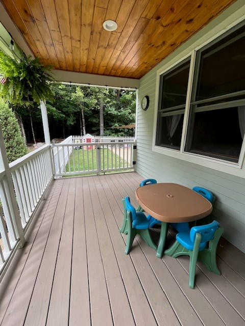 Porch with a small table and chairs, overlooking a fenced yard