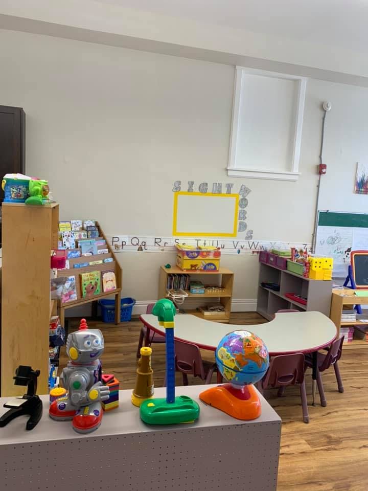 Classroom with small tables and chairs, bookshelves, and toys
