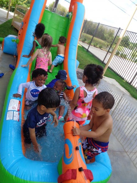Children playing on an inflatable water slide and in a shallow pool