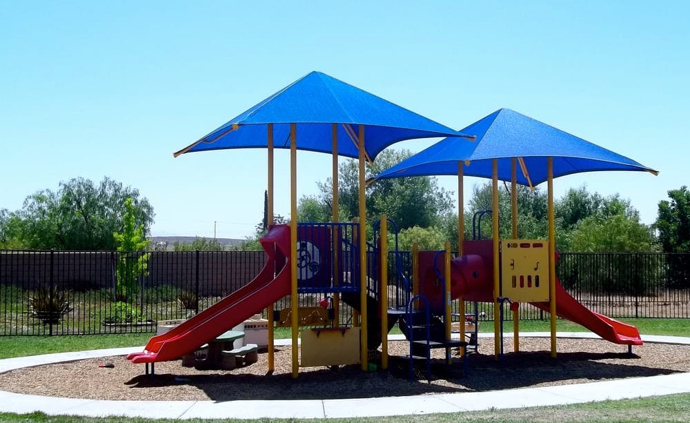 Playground with blue shade canopies and red slides