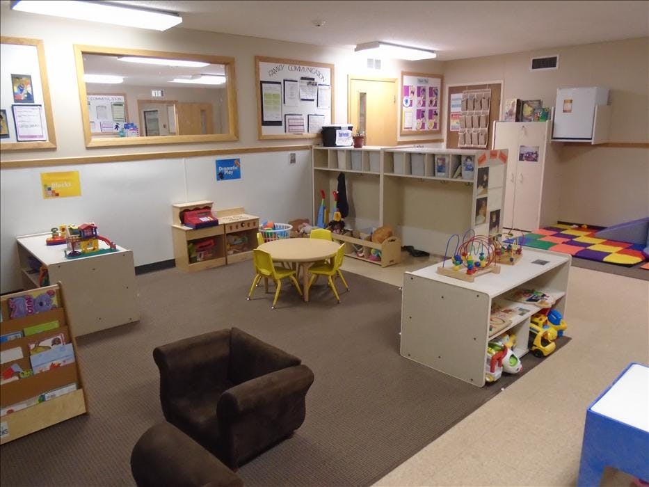 Children's playroom with toys, a small table, chairs, and shelves