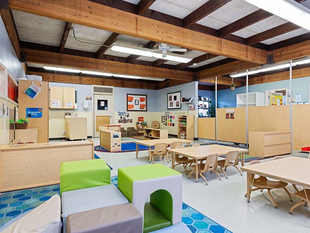 Empty classroom with small tables and chairs, modular seating, and cubbies