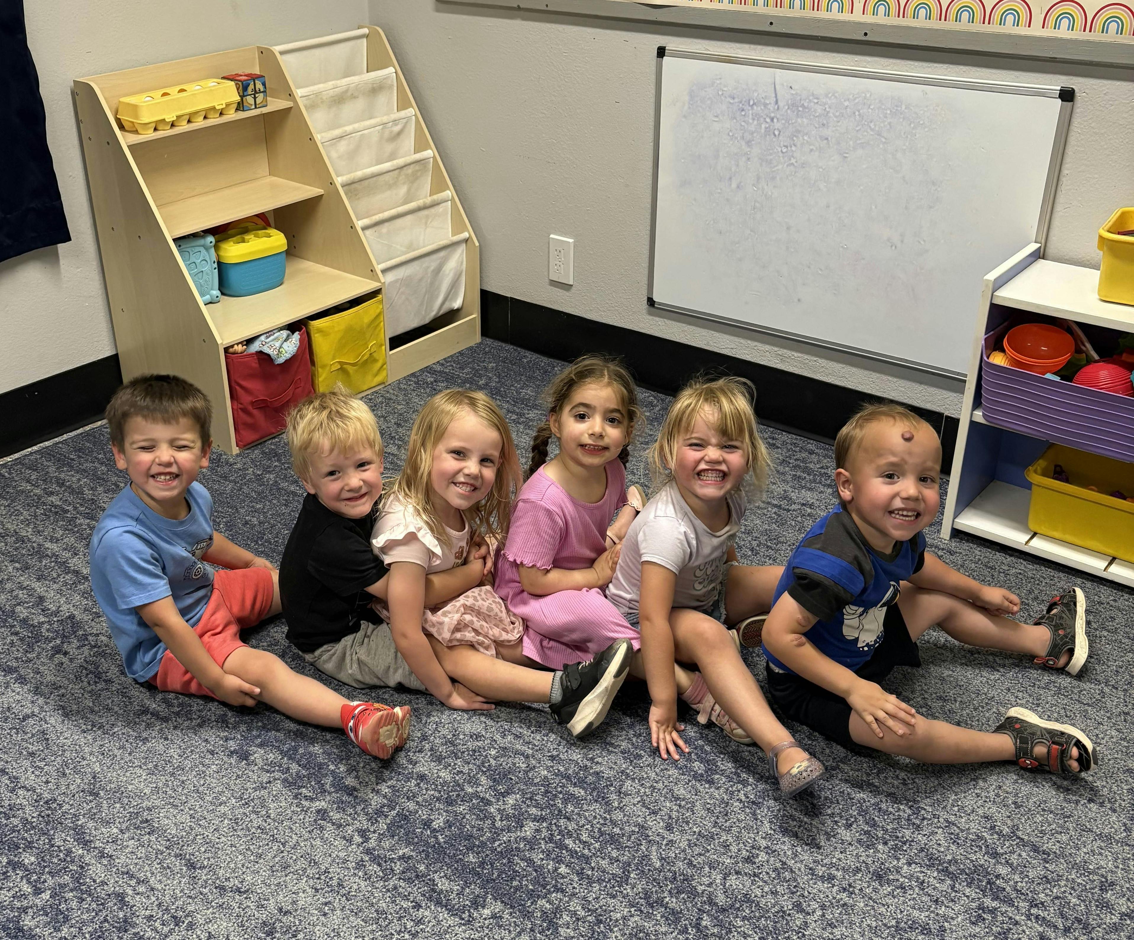 Five children sitting on the floor in a classroom