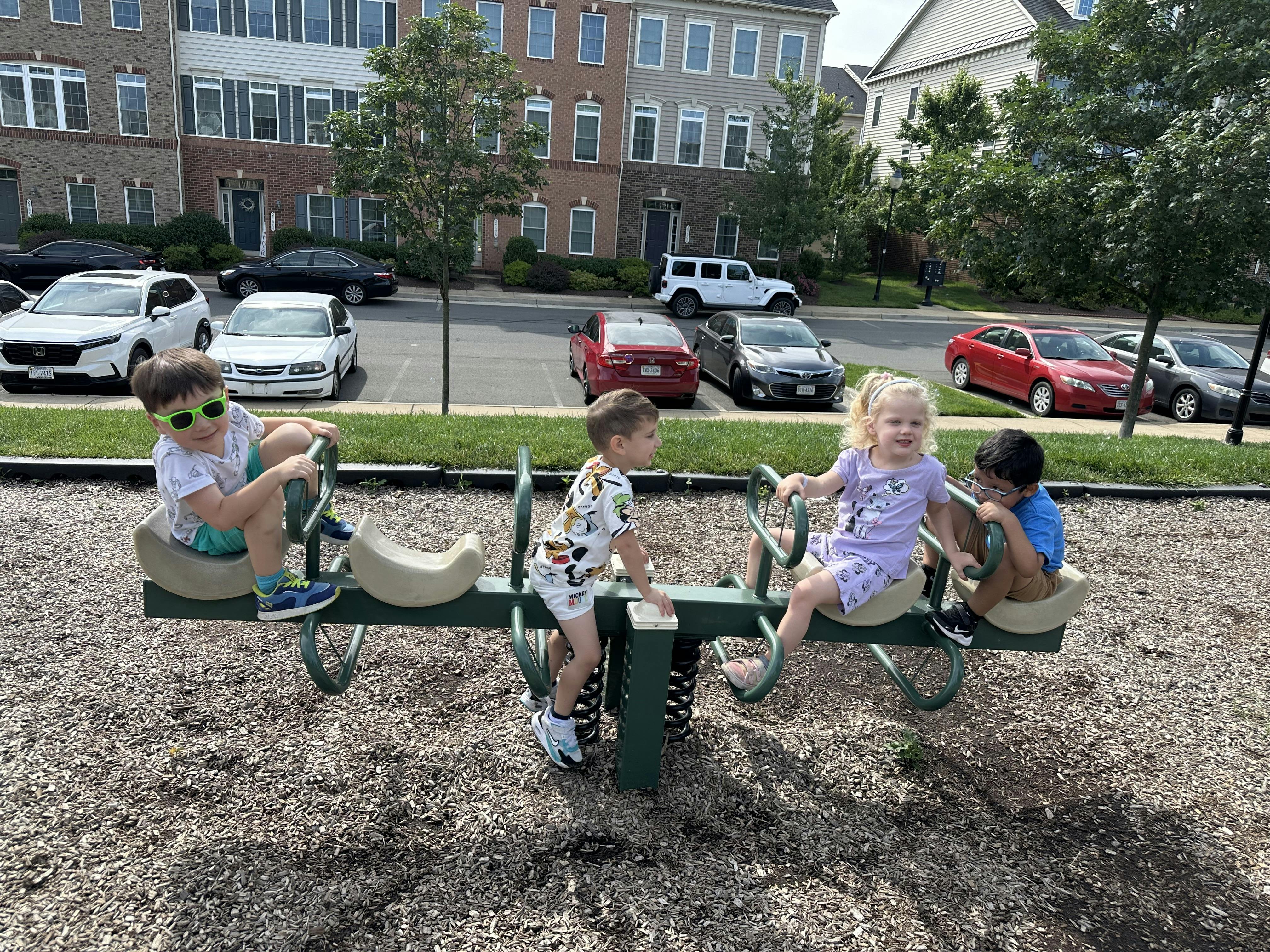 Four children playing on a seesaw on a playground