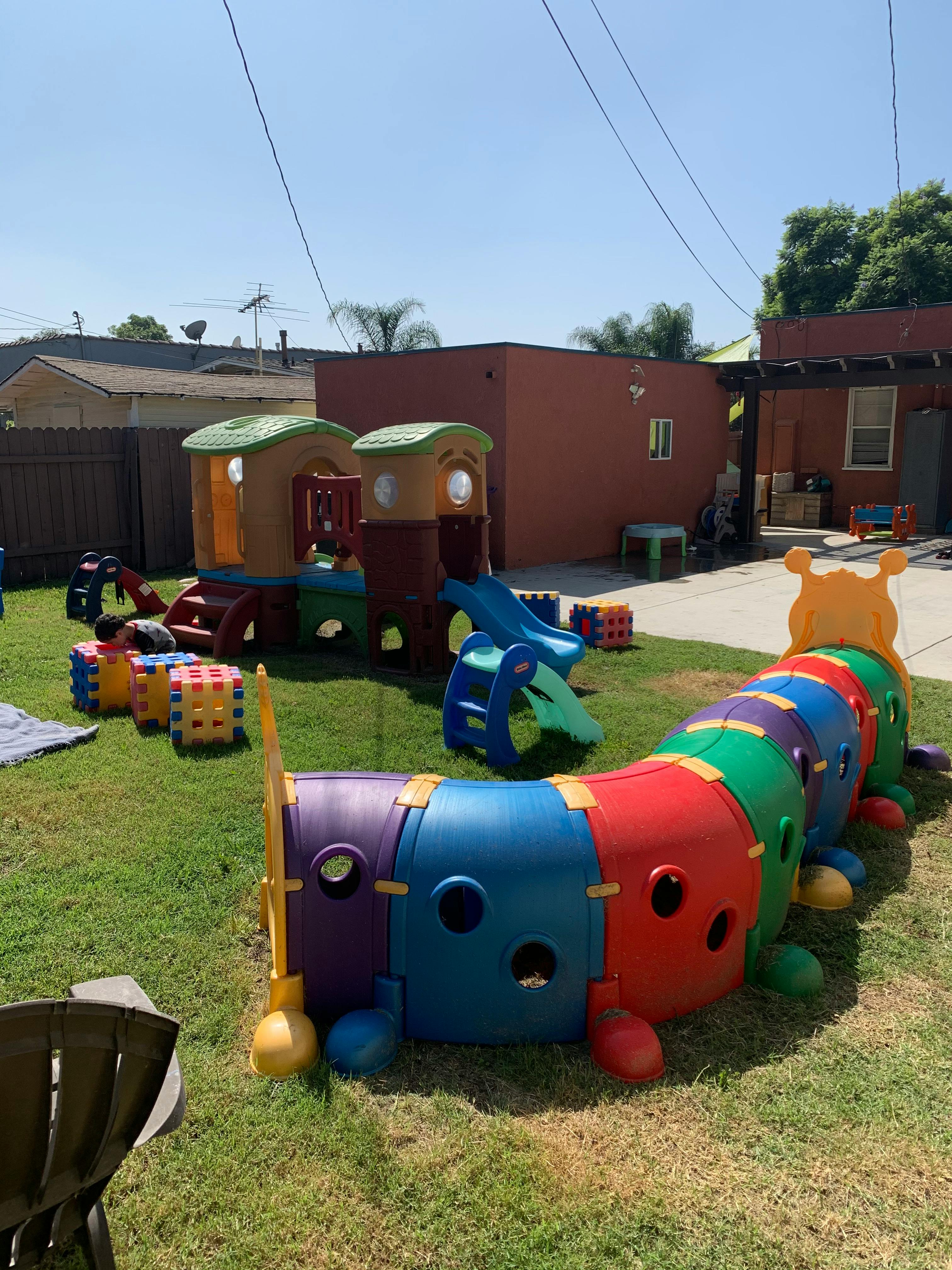 Playground with a caterpillar tunnel and playhouse with slides