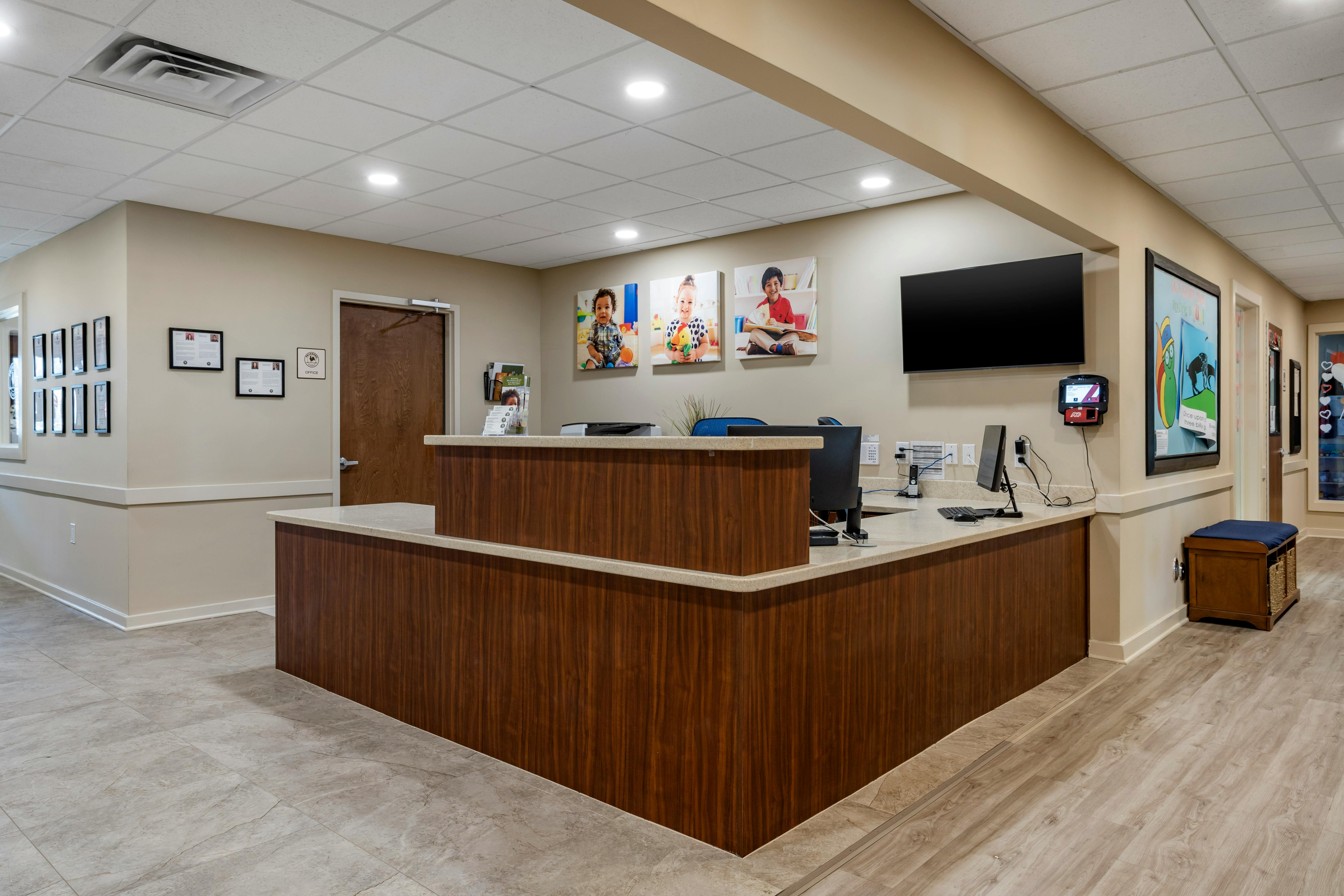 Reception desk with three photos of children on the wall behind it