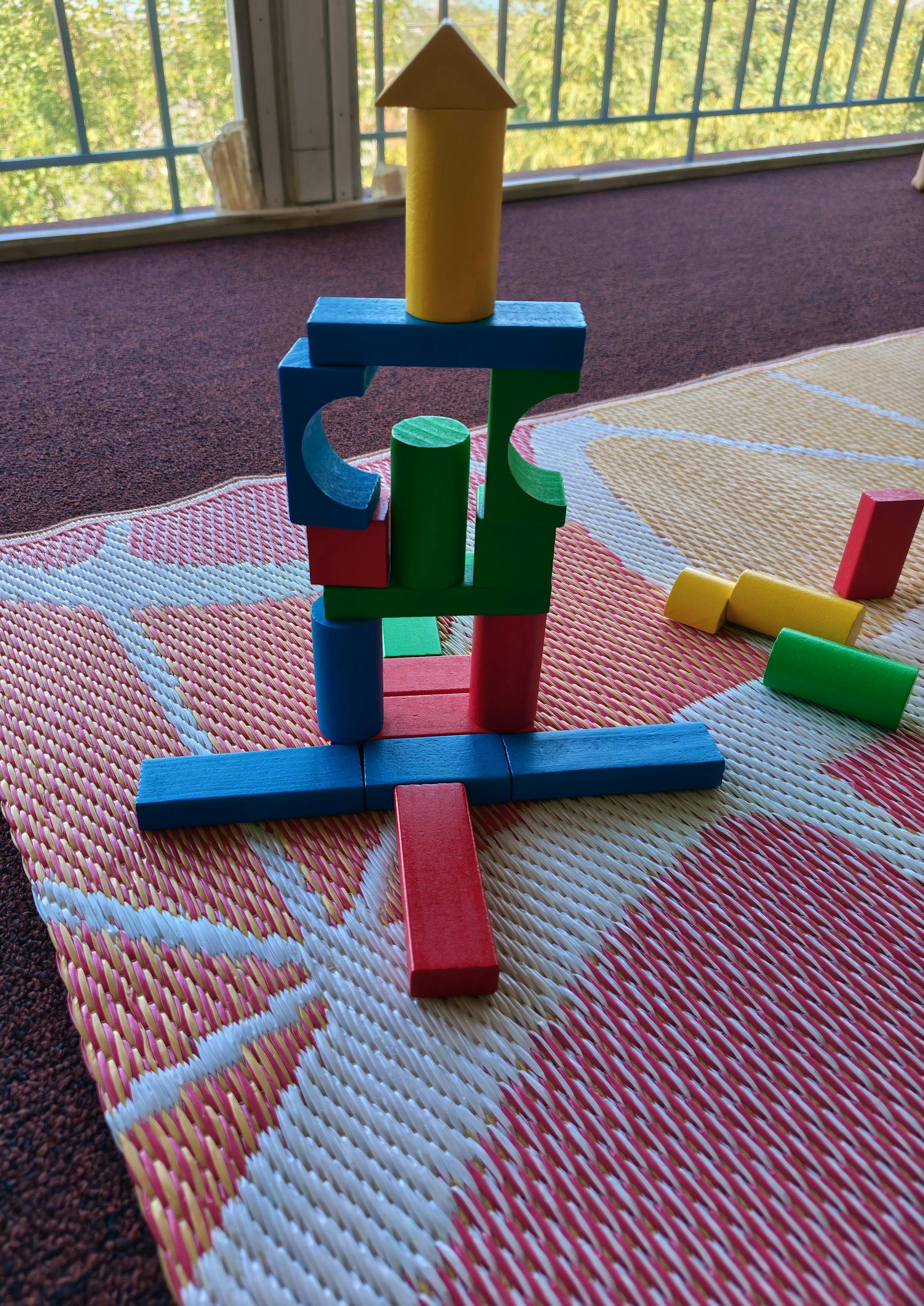 A tower made of stacked colorful wooden blocks on a patterned mat