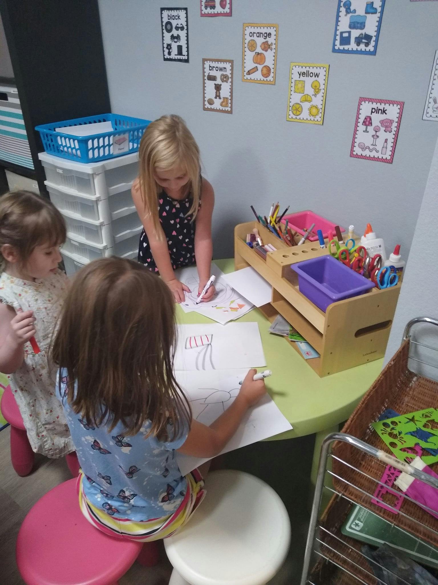 Three children drawing at a table