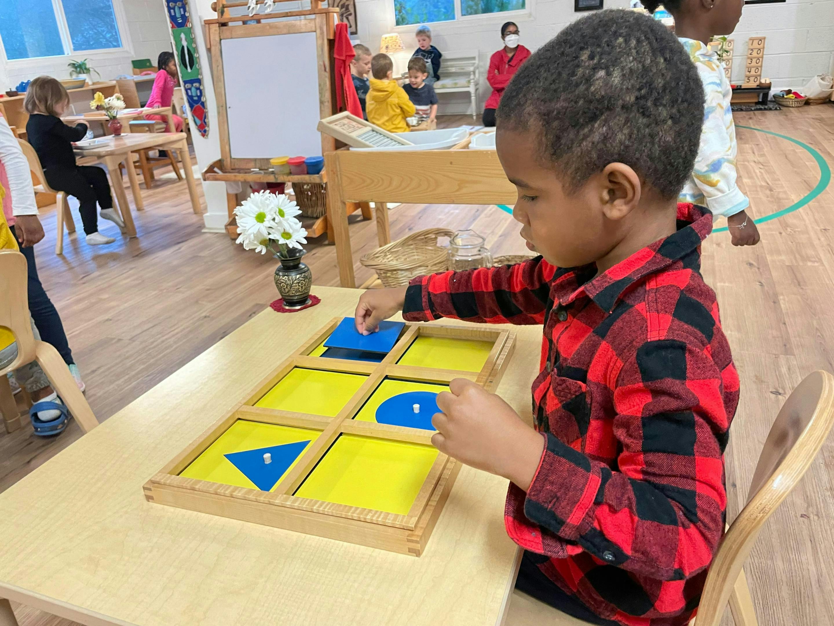 Child playing with geometric shape puzzle in a classroom