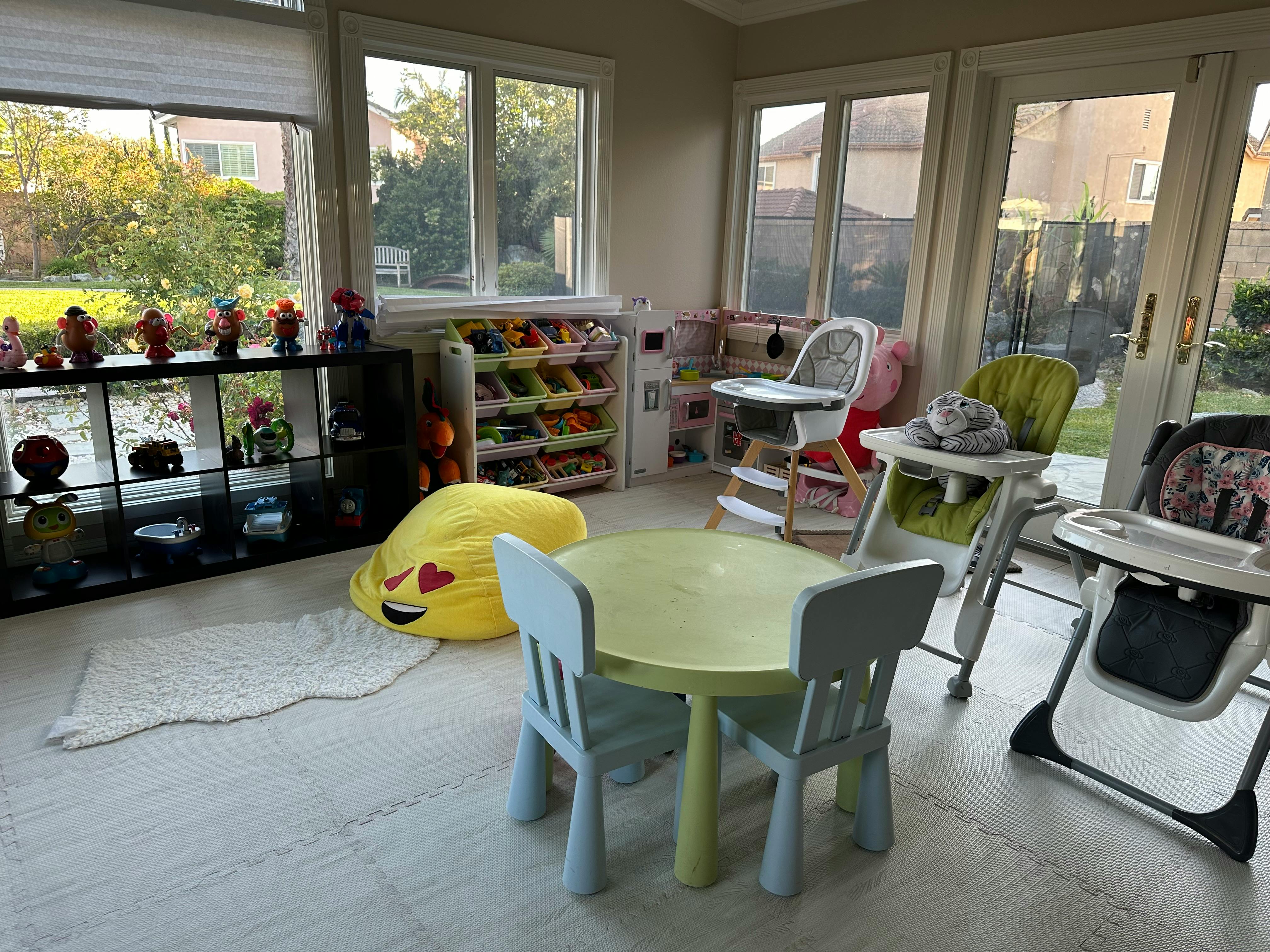 Children's play area with small table and chairs, high chairs, and toy storage