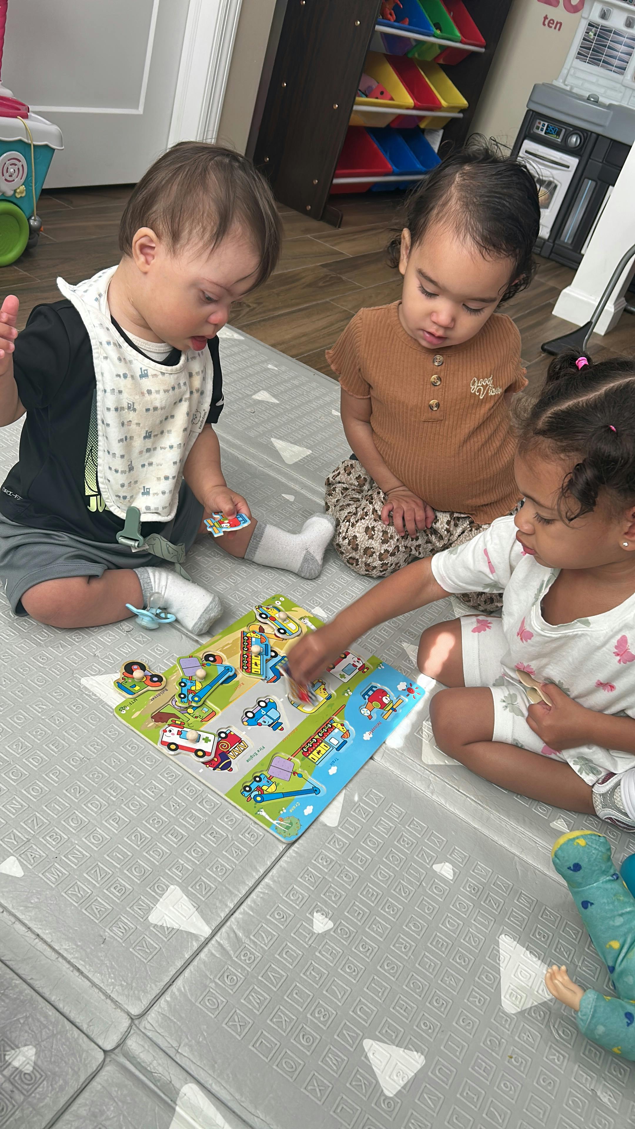 Three children playing with a puzzle on a floor mat
