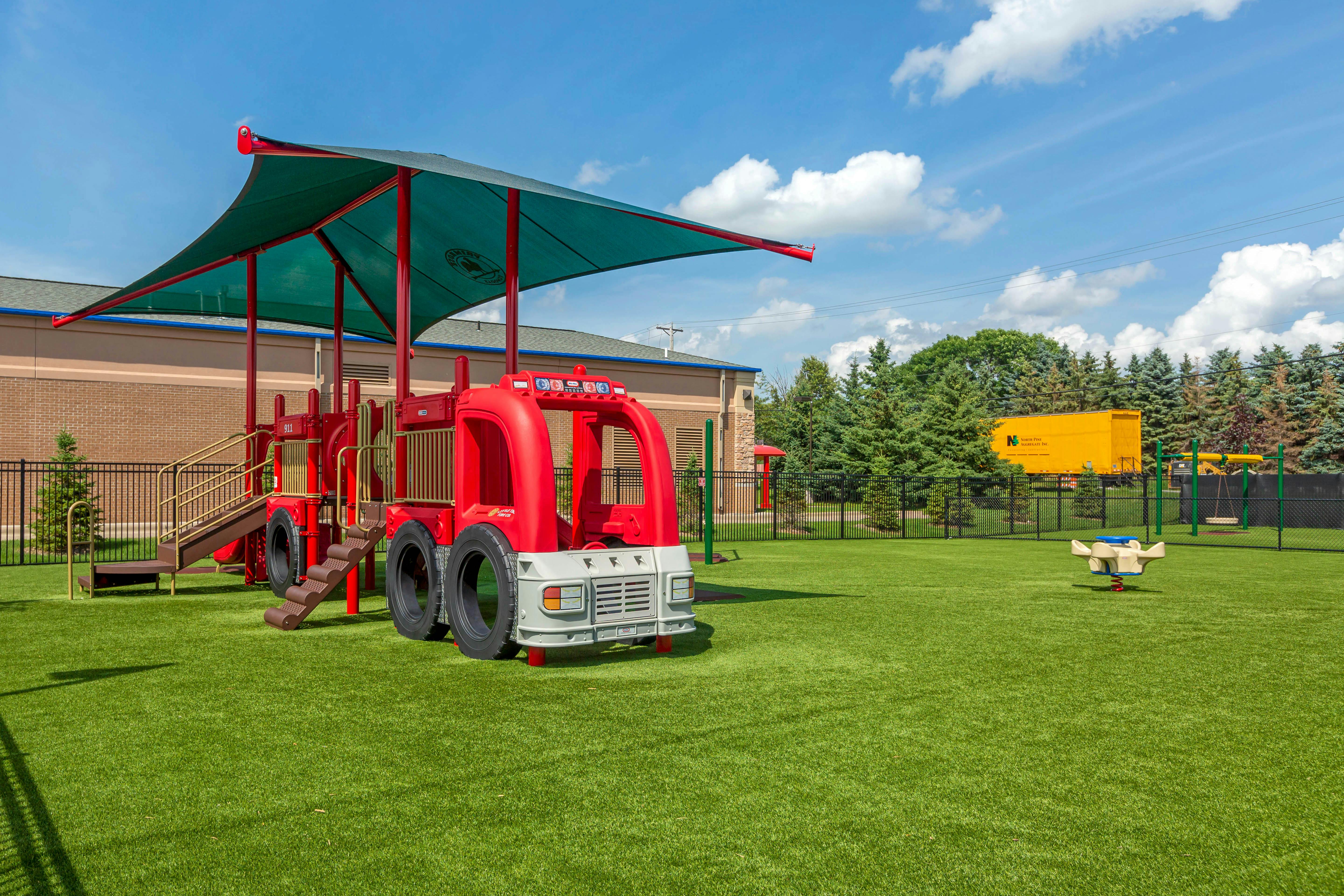 Playground with a red fire truck play structure and a spring rider