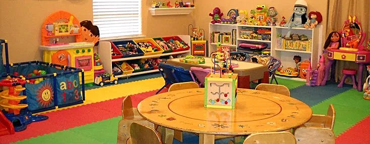 Playroom with small tables and chairs, toy shelves, and play structures