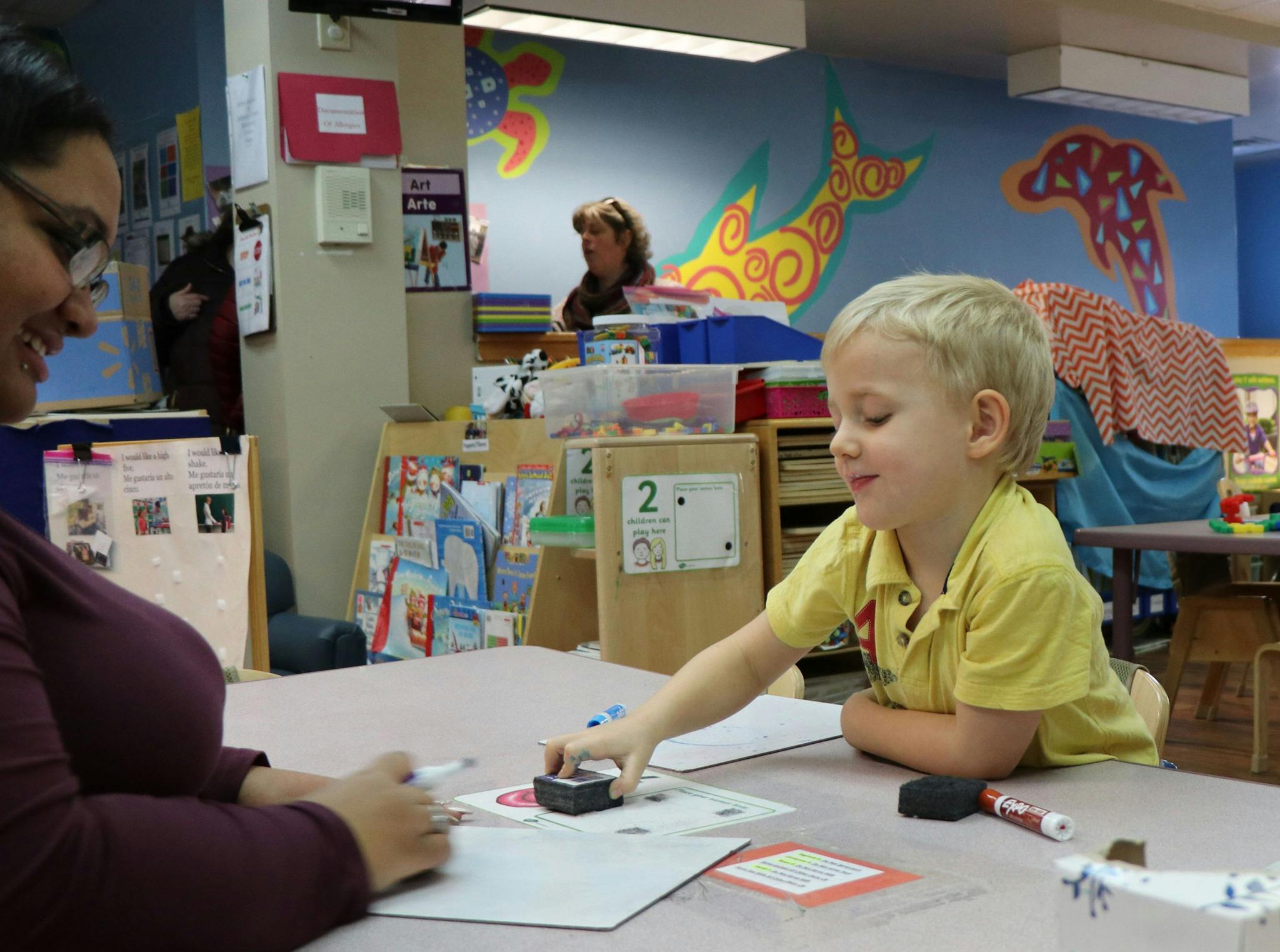 Adult and child at a table with papers and a stamp