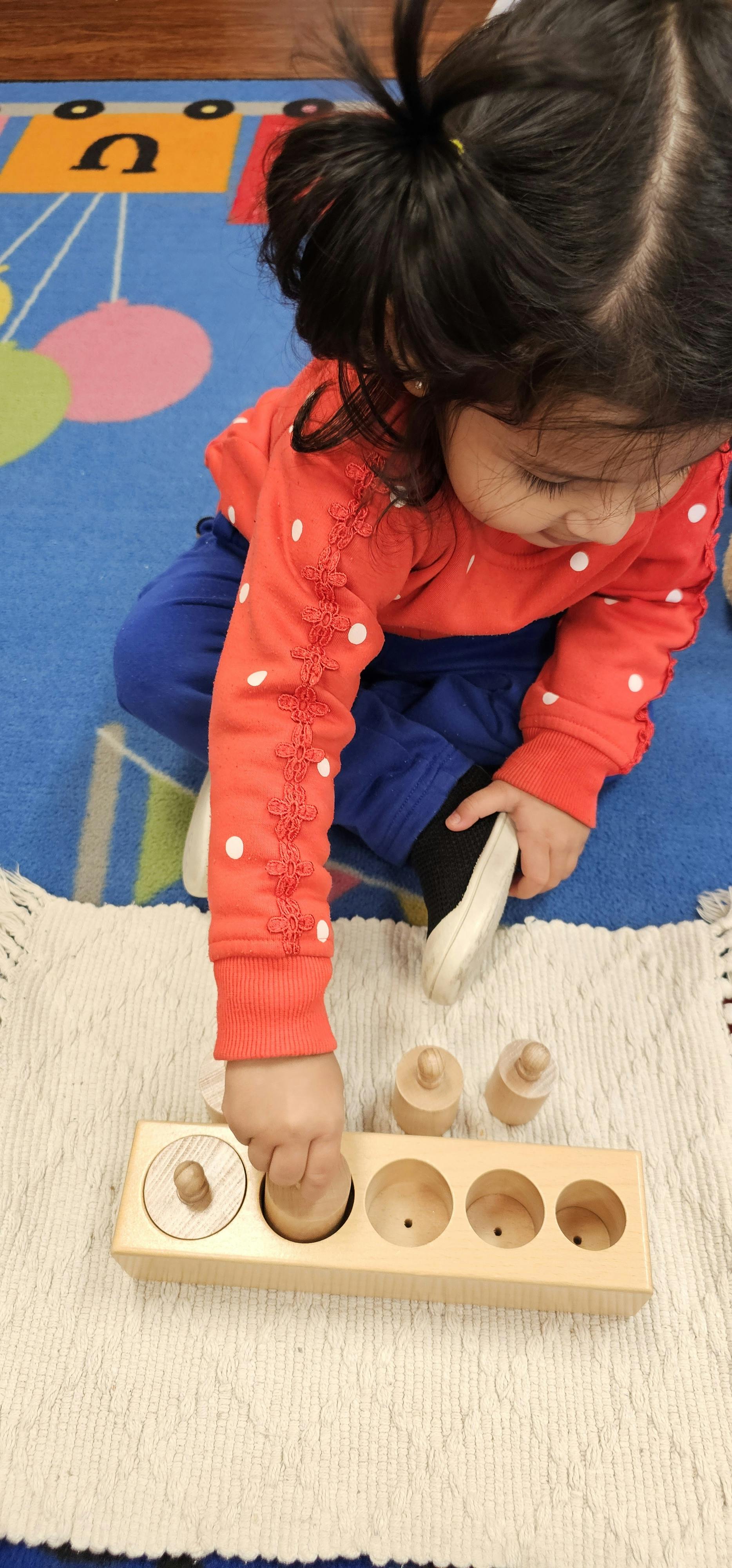 Child playing with a wooden cylinder block puzzle