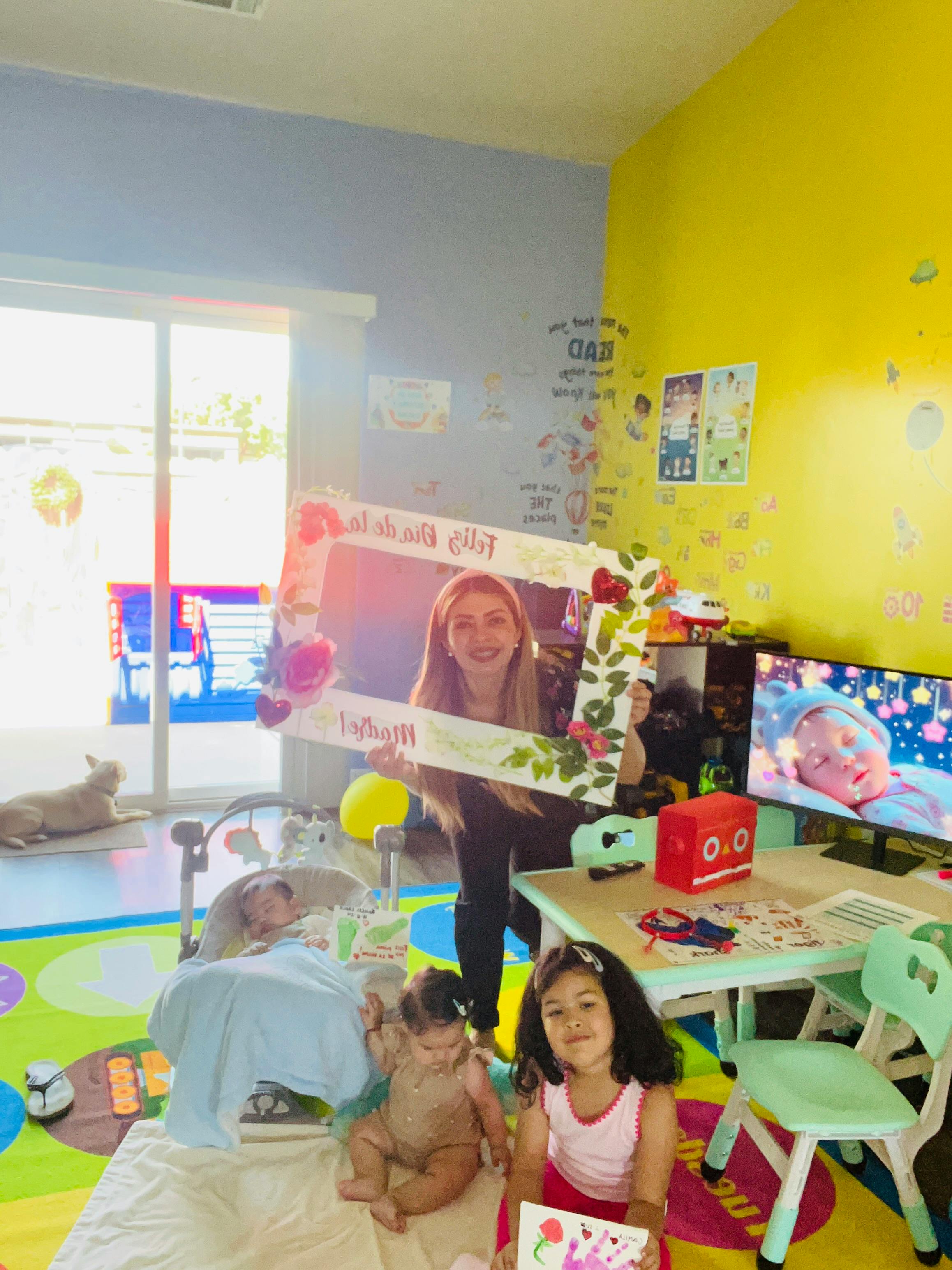 Person holding a decorative frame with two children sitting on the floor