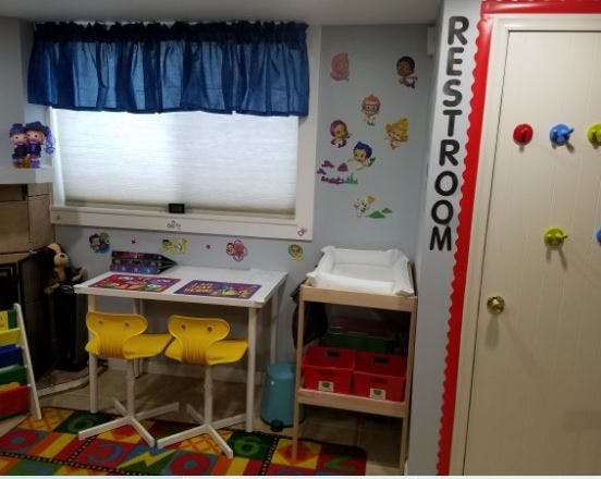 Children's play area with small table and chairs, changing station, and a door labeled RESTROOM