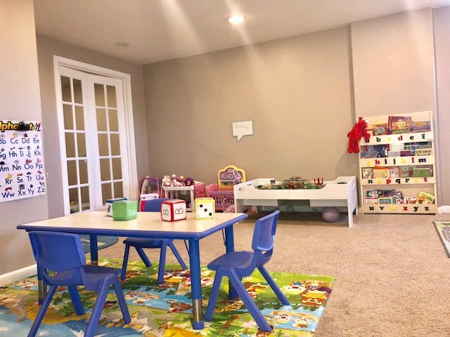 Children's play area with a table and chairs, toys, and a bookshelf