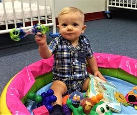 Child sitting in an inflatable playpen holding a toy