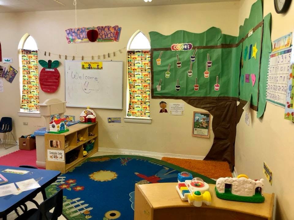 Classroom with a whiteboard, colorful rug, and tree-shaped wall decoration