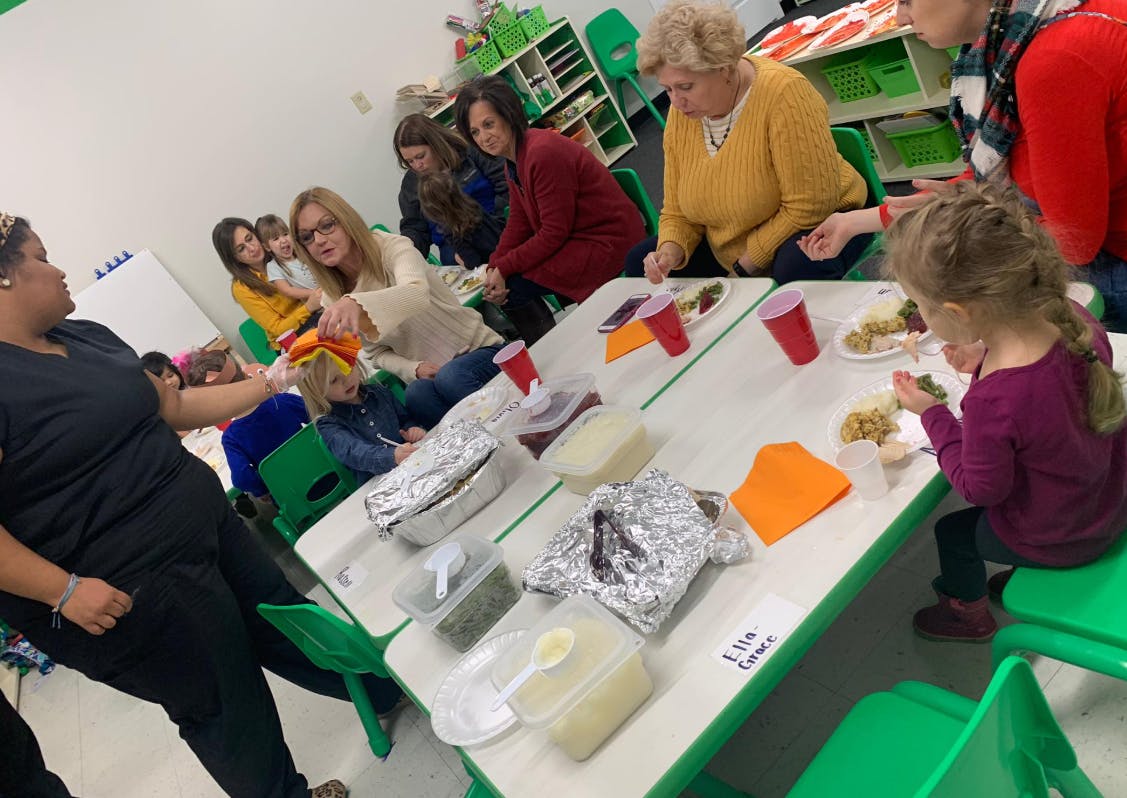 People and children eating at tables in a classroom
