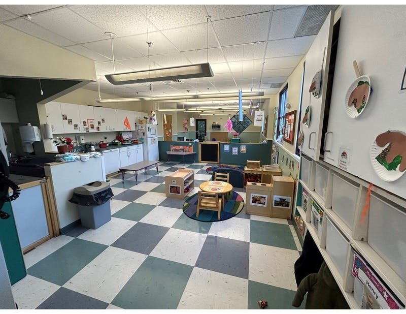 Empty colorful classroom with small furniture, a play kitchen, and checkered floors