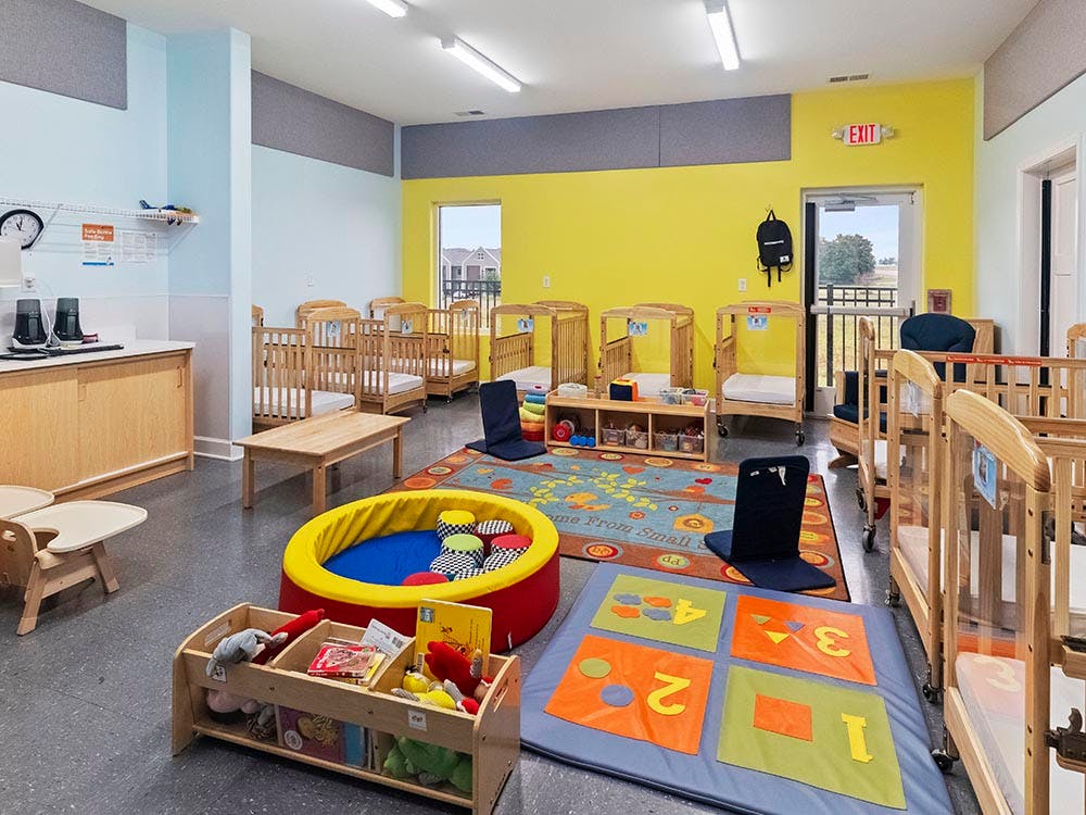 Baby room with multiple cribs, a playmat with numbers, and a ball pit