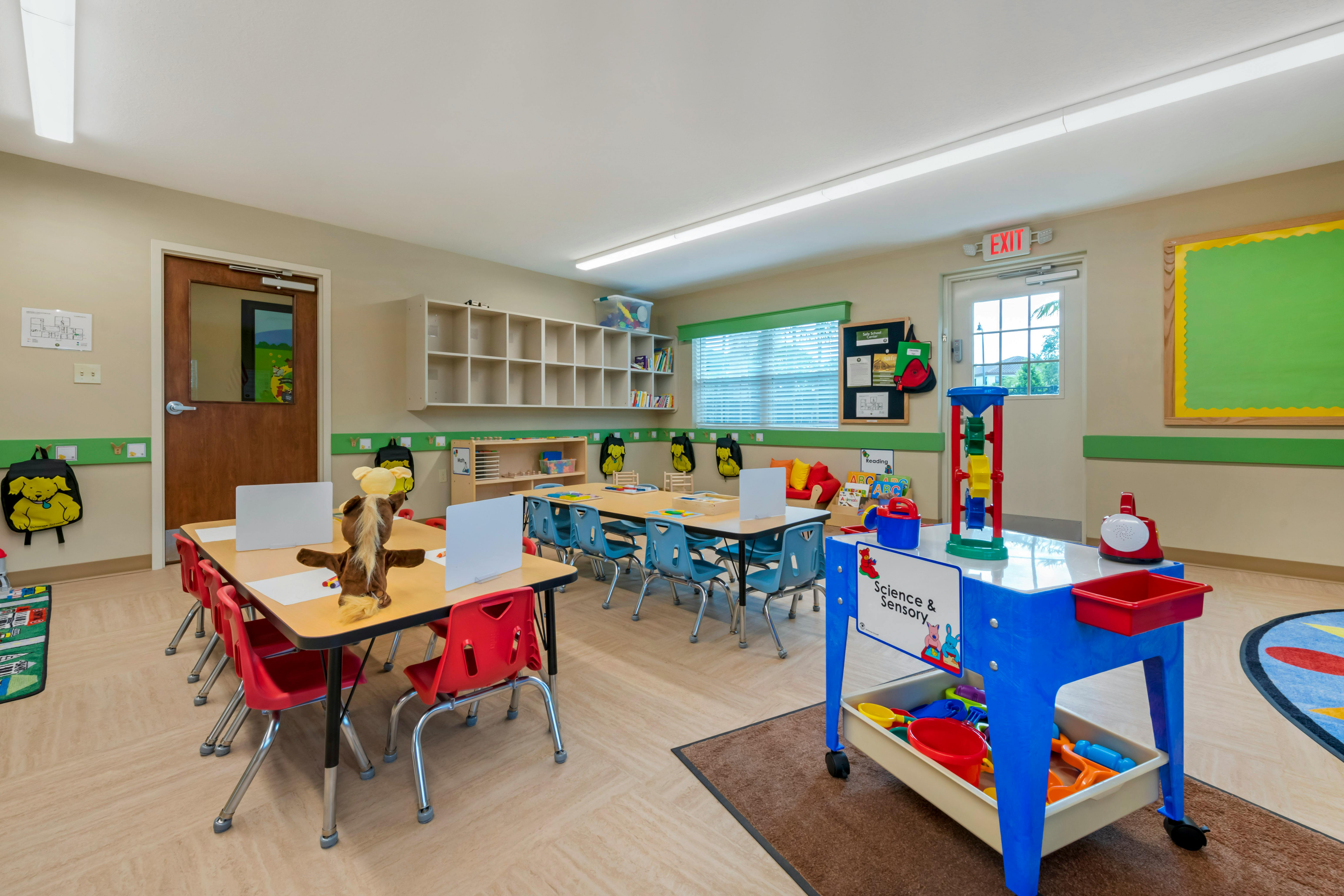 Classroom with child-sized tables and chairs, cubbies, and a "Science & Sensory" station