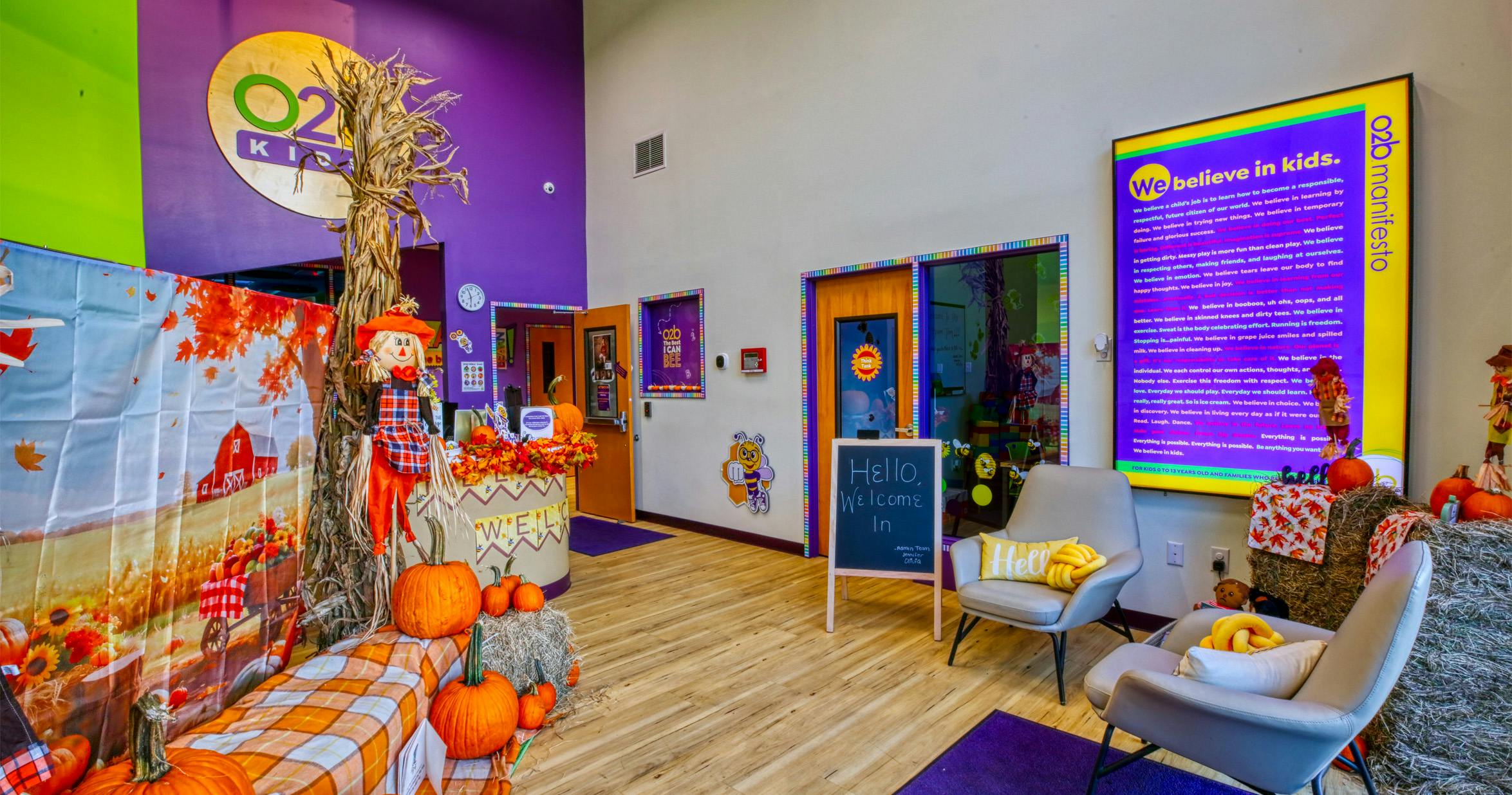 Lobby area decorated for fall with scarecrows, pumpkins, and a large sign with text
