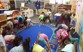 Children and adults stretching in a classroom