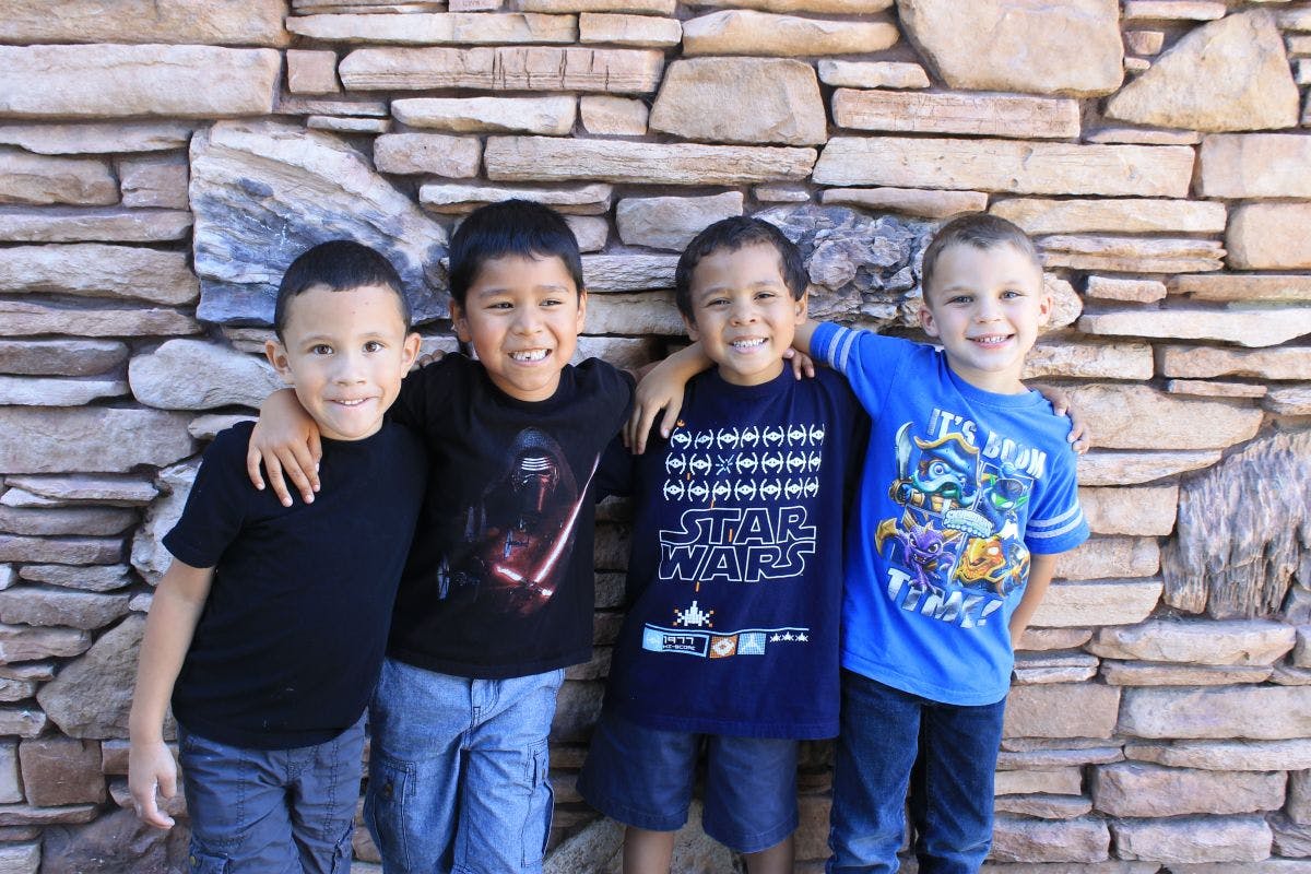 Four children standing with arms around each other