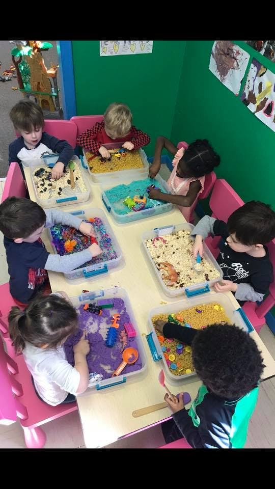 Children playing with sensory bins at a table