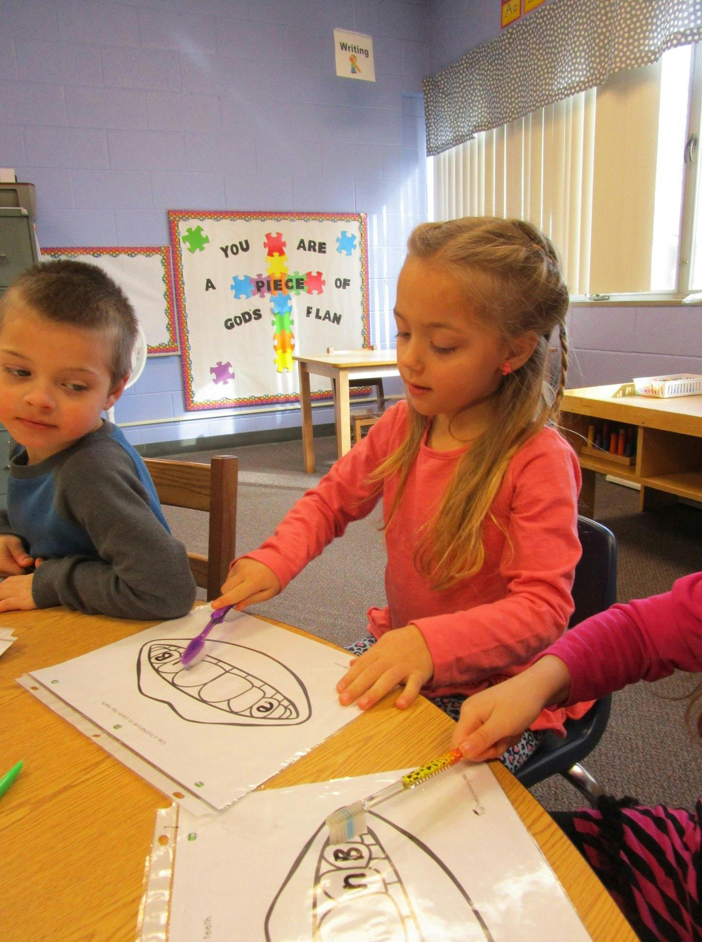 Child coloring a drawing at a table in a classroom