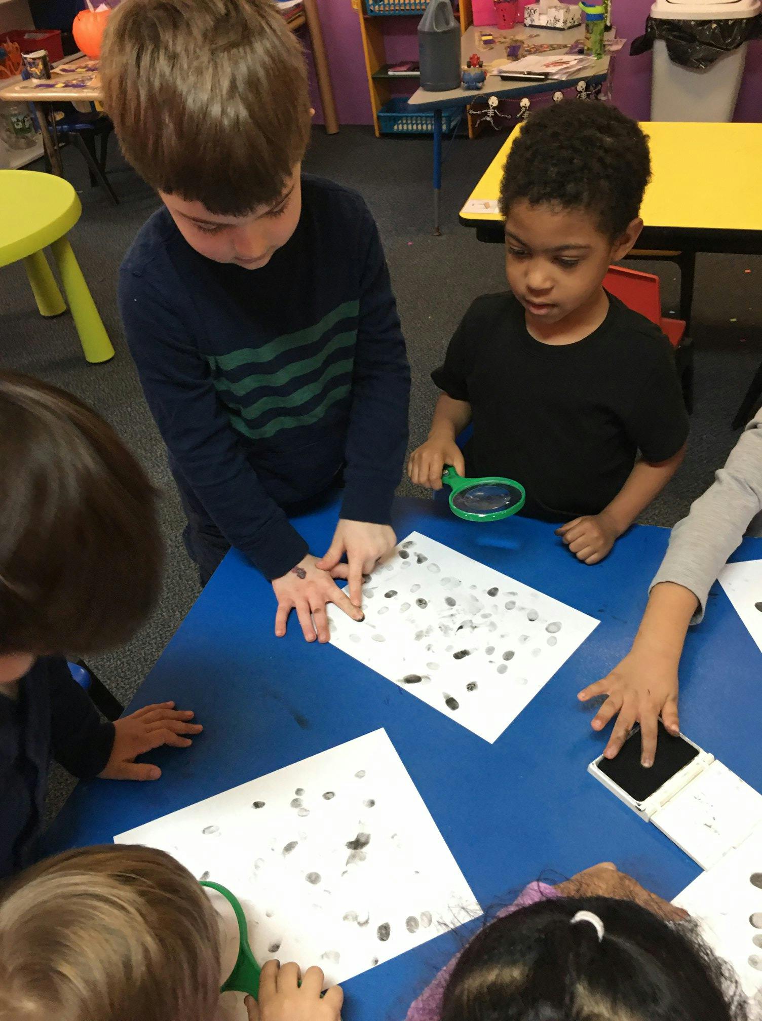 Children looking at papers with fingerprints on a blue table