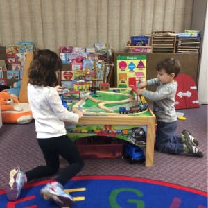 Two children playing with a toy train set on a table