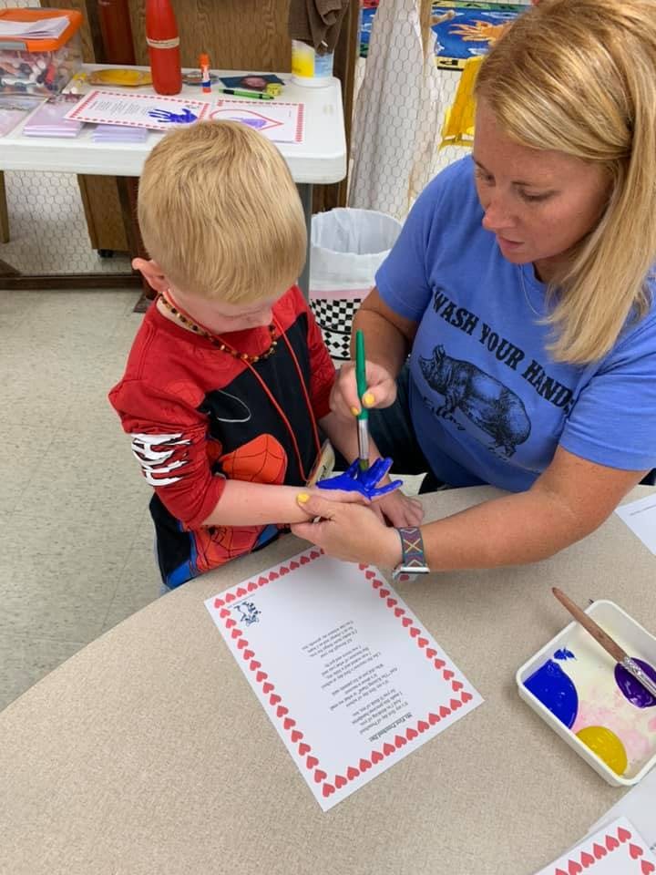 Adult and child painting a small blue object