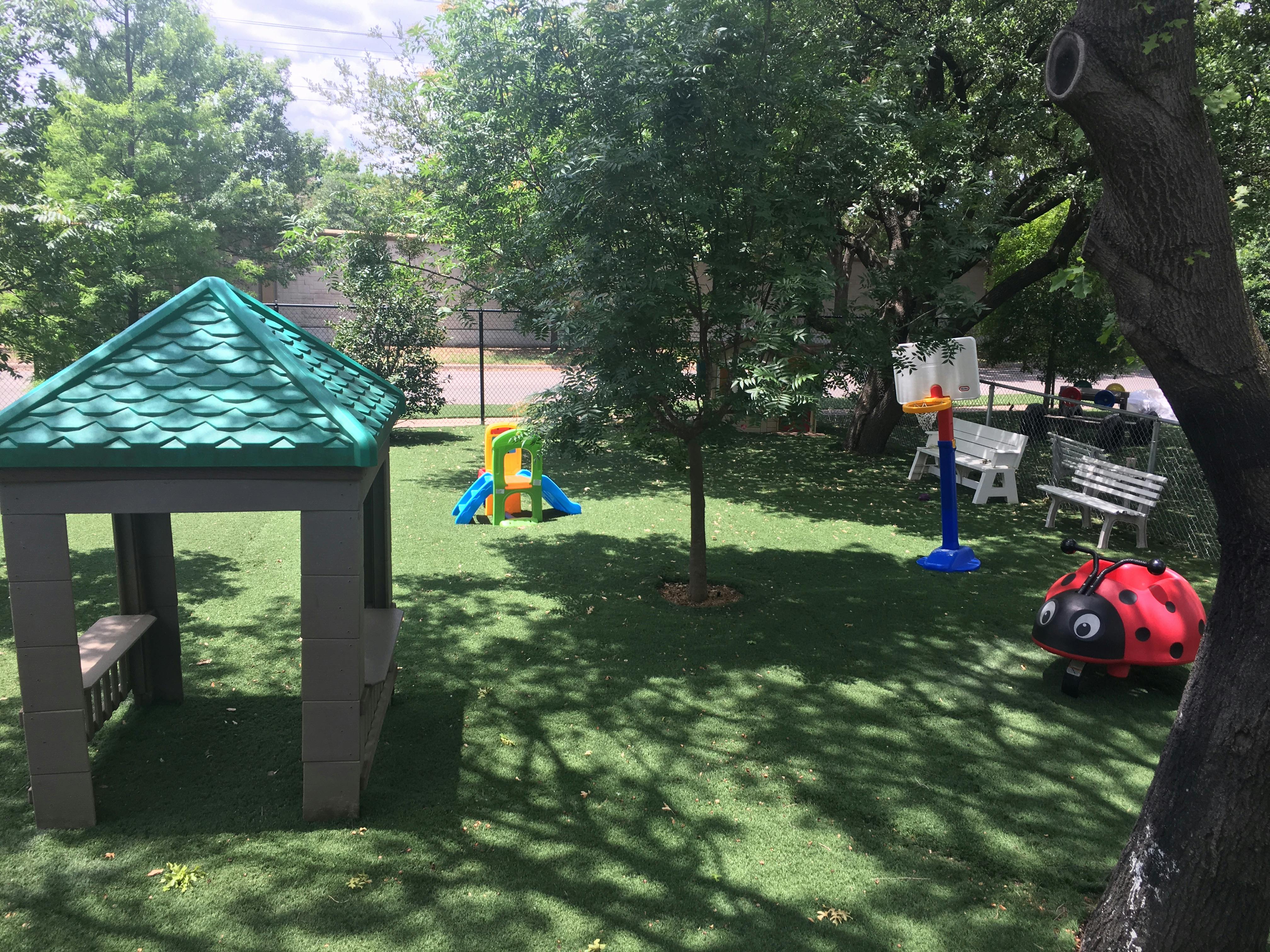 Playground with a green gazebo, slide, basketball hoop, and ladybug toy
