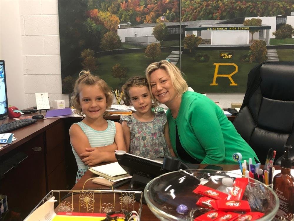 Adult and two children posing for a photo at a desk