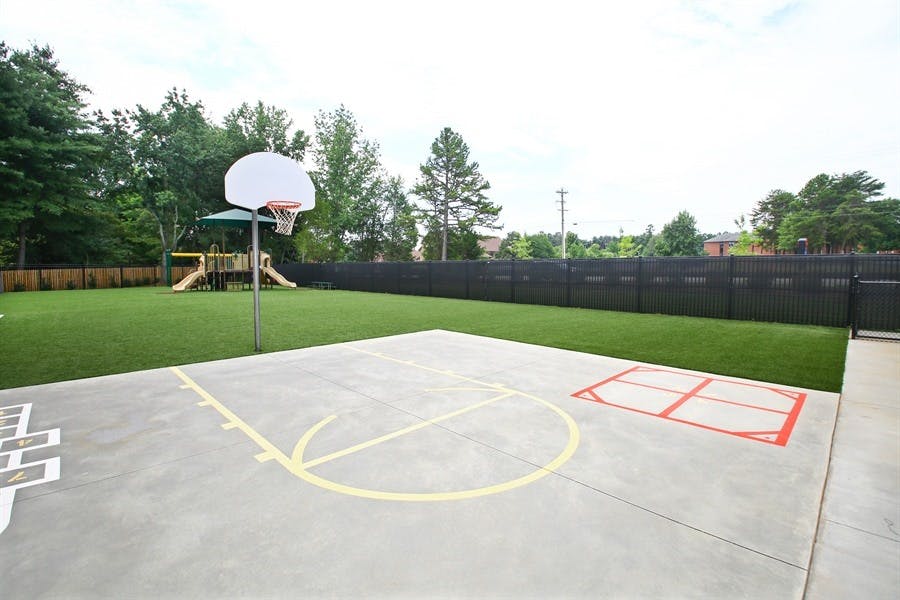 Outdoor basketball court with a hoop and playground in the background